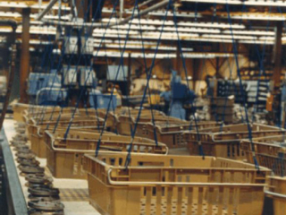 Overhead conveyor used to transport small motor components during assembly process in suspended totes.
