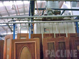 Large wooden doors hang from Pacline enclosed track conveyor to transport from finishing through assembly process