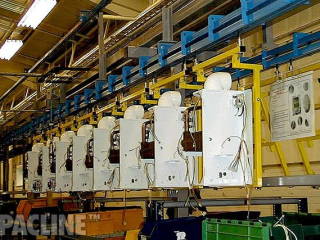 A PACLINE Power and Free conveyor carrying large water heaters through assembly process.