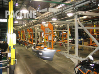Overhead I Beam trolley conveyor transports large automobile bumpers through assembly process