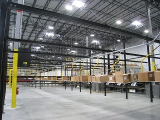 Overhead monorail conveyor for delivery and removal of corrugated cartons in distribution center.