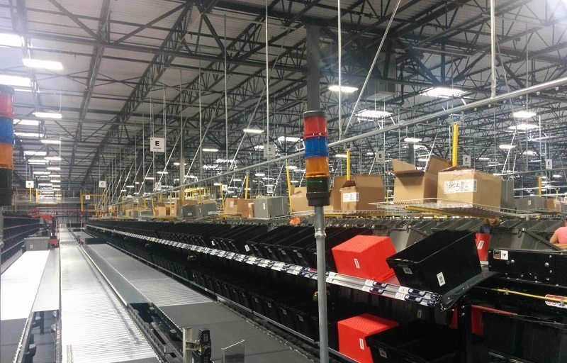 Conveyor system for empty tote delivery nd corrugated carton removal in warehouse.
