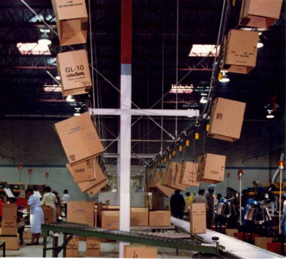 Monorail conveyor delivering empty cartons above operators Monorail conveyor delivering empty cartons