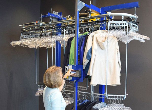Operator loading garments onto coat check conveyor