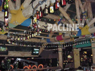 A PAC-LINE™ conveyor keeps beer bottles moving continuously overhead in bar for a creative display.