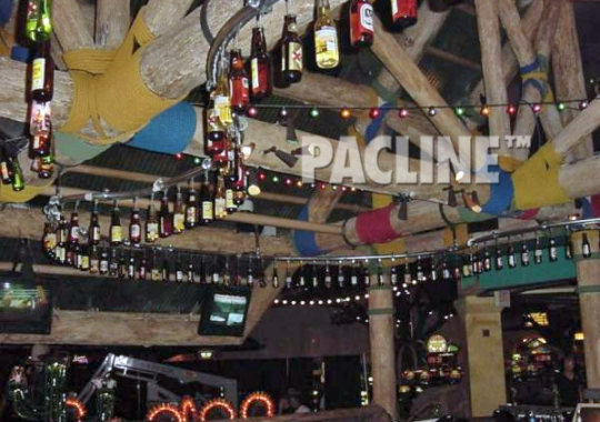 A PAC-LINE™ decorative conveyor keeps beer bottles moving continuously overhead in bar for a creative display.