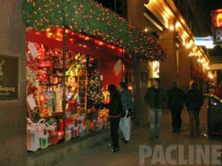 Hudson Bay store window attracts customers with a display animated by a conveyor moving gifts in Santa&#039;s workshop.