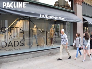 Pedestrians view The Hudson&#039;s Bay creative window display created using a PAC-LINE™ overhead conveyor.