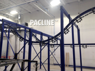 Overhead I beam conveyor has tight curves designed to handle parts through dip line finishing system.
