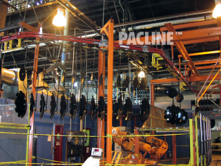Power and free conveyor transfers heavy metal parts through dip paint line, annealing oven and shot blast.