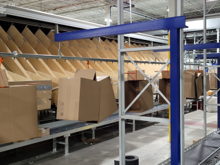 Warehouse overhead conveyor for delivering boxes in packing facility