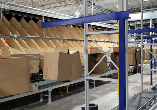 Warehouse overhead conveyor for delivering boxes in packing facility