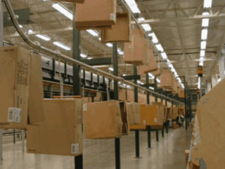 Empty cartons are delivered to automatic sorter packing stations. Conveyor with two tier floor support.