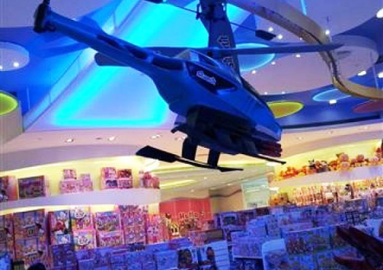 An decorative overhead conveyor carries a Helicopter above store patrons in a Macau toy store.