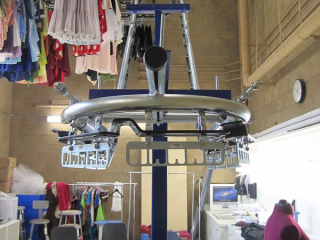Small costume storage room uses overhead space where garments are protected and floor space can be free for other uses.