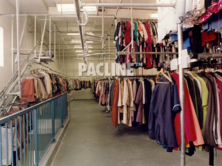 Garment storage and retrieval conveyor takes items up steep incline to second floor warehouse.