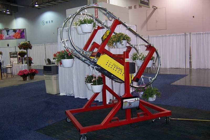 Enclosed track conveyor system for handling hanging plants in greenhouses and growing operations.