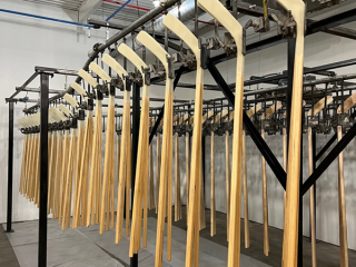 Overhead conveyor paint line for hockey sticks