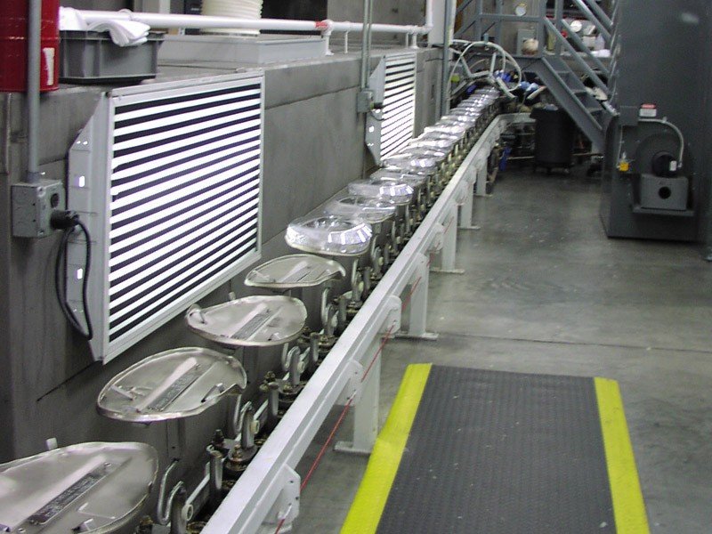 Heavy duty inverted conveyor carrying metal parts through a chemical wash.