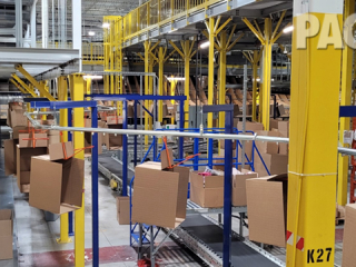 Overhead conveyor for delivering empty boxes in a packing facility