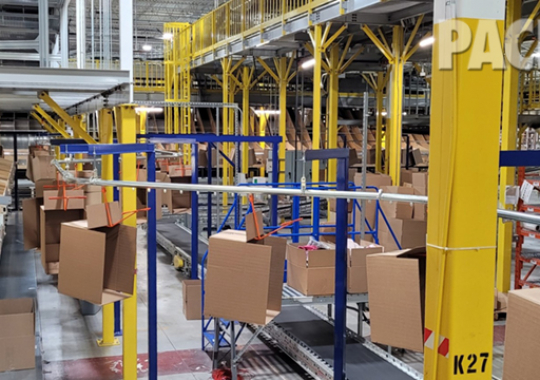 Overhead conveyor for delivering empty boxes in a packing facility