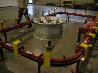 Sideways oriented, enclosed track conveyor for finishing automotive rims on sprocket rotatable spindles.