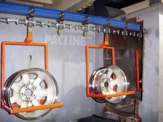 Overhead monorail conveyor carries auto wheel rims through wash system before electroplating process.