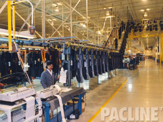 Buffer storage of automotive parts at ceiling, Enclosed track conveyor feeding overhead I-beam assembly conveyor.