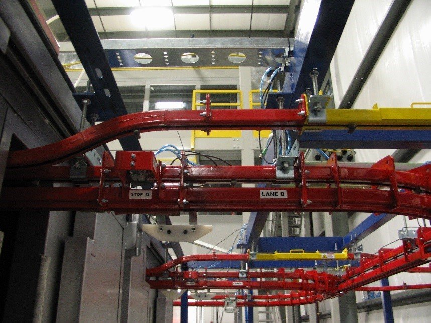 Power and free overhead conveyor for wet spray application.