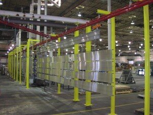 Power and free overhead conveyor carrying long parts through washer system