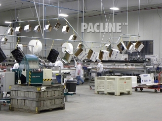 Conveyor moves empty cartons on hooks in apple packing shed.