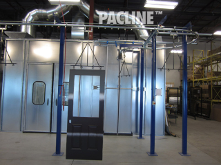 Compact overhead conveyor moves Masonite doors through wet spray paint booth and drying ovens.