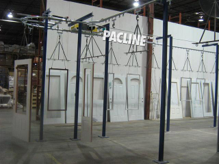 Single line overhead conveyor transfers wooden doors and windows through various stages of paint finishing.