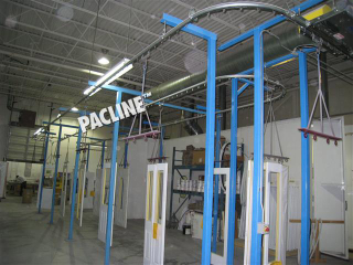 Automated spray paint line uses overhead conveyor to handle tall wooden doors.