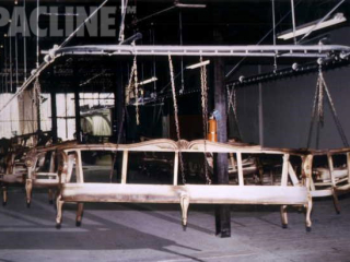Enclosed track overhead conveyor transfers wooden sofa frames through paint finishing lines.
