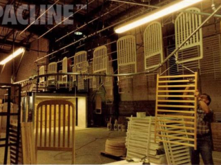 Monorail enclosed track conveyor moves wooden bed frames through sanding and paint finishing.